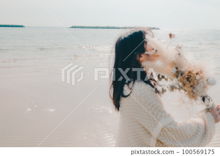 海邊拿著乾花的女人照片 100569175