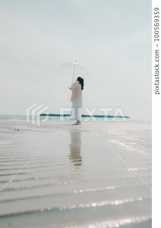 Photo of a woman listening to music on the beach 100569359