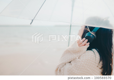 一個女人在沙灘上聽音樂的照片 一個女人在沙灘上聽音樂的照片 100569370