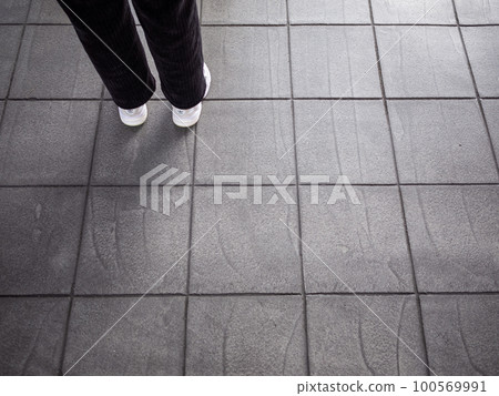 [Japan] Tokyo, both feet of a person standing on the grid-like tile ground 100569991