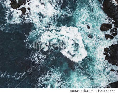 Stormy sea on a cold autumn day, top down view at the waves crushing over the rocks 100572272