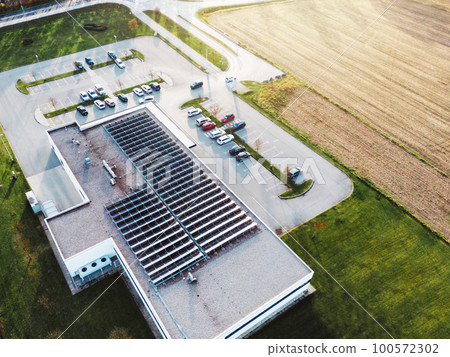 Aerial view of an industrial building with solar panels on the roof 100572302