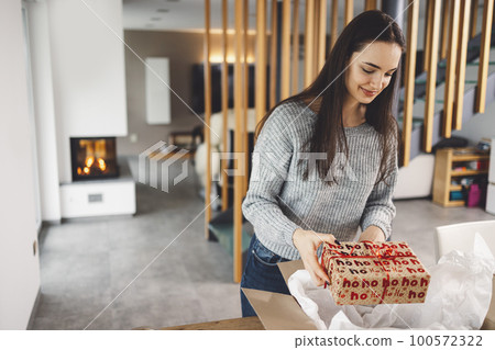 Happy caucasian woman holding a Christmas present she has just taken out of the box that came in the mail  100572322