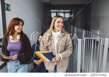 Group of friends, thre young woman laughing while walking in the college dorm Group of friends, thre young woman laughing while walking in the college dorm 100572348