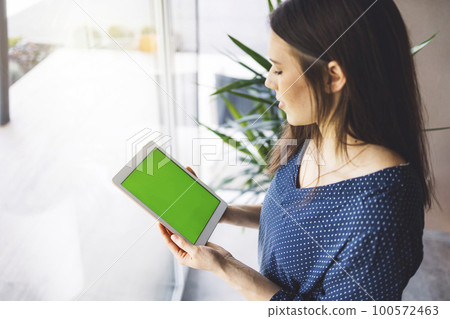 Top down view, over the head shot, woman holding a tablet with green screen Top down view, over the head shot, woman holding a tablet with green screen 100572463