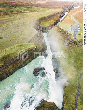 Vertical photo of Gullfoss waterfall in autumn time of the year, vibrant green hills surrounding the waterfall Vertical photo of Gullfoss waterfall in autumn time of the year, vibrant green hills surrounding the waterfall 100572482