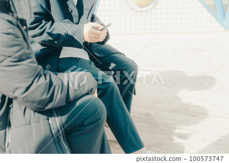 A picture of a male college student touching a smartphone in the park 100573747