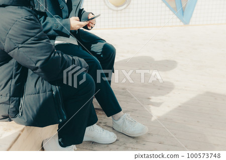 一張男大學生在公園裡摸智能手機的照片 100573748