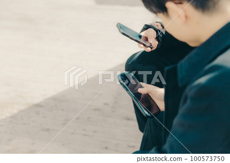 A picture of a male college student touching a smartphone in the park A picture of a male college student touching a smartphone in the park 100573750