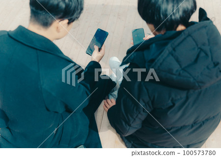 A picture of a male college student touching a smartphone in the park A picture of a male college student touching a smartphone in the park 100573780