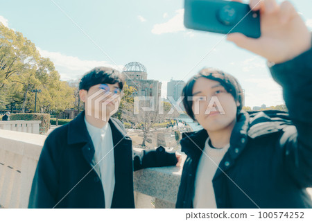 Photo of a male university student taking a commemorative photo at a sightseeing destination 100574252