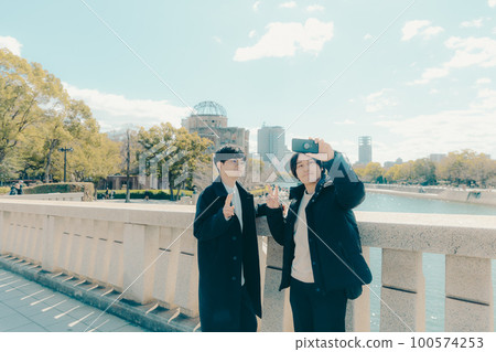 Photo of a male university student taking a commemorative photo at a sightseeing destination 100574253