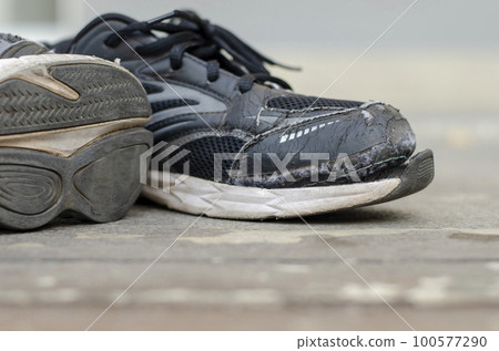 Old black sneakers torn after a long time of use. 100577290