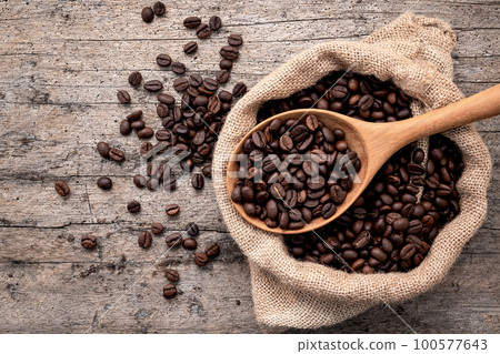 Background of dark roasted coffee beans with scoops setup on wooden background with copy space. Background of dark roasted coffee beans with scoops setup on wooden background with copy space. 100577643
