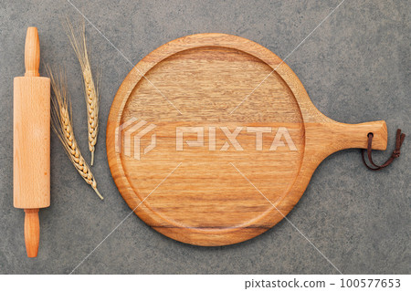 Empty wooden pizza platter set up on dark concrete. Pizza tray on dark concrete background flat lay and copy space. Empty wooden pizza platter set up on dark concrete. Pizza tray on dark concrete background flat lay and copy space. 100577653