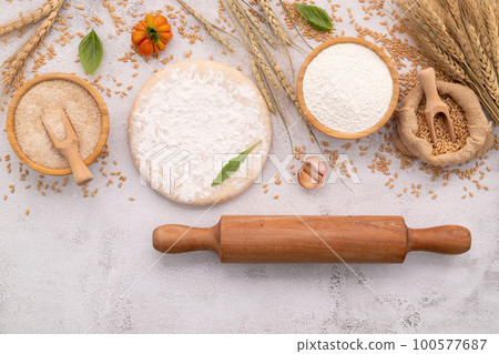 The ingredients for homemade pizza dough with wheat ears ,wheat flour and wheat grains set up on white concrete background. 100577687