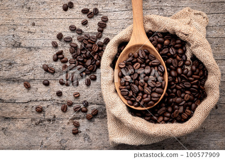 Background of dark roasted coffee beans with scoops setup on wooden background with copy space. Background of dark roasted coffee beans with scoops setup on wooden background with copy space. 100577909