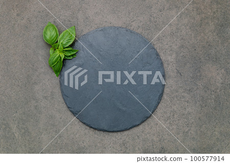 Empty pizza platter for homemade baking set up on dark concrete. Food recipe concept on dark stone background texture with copy space. Empty pizza platter for homemade baking set up on dark concrete. Food recipe concept on dark stone background texture with copy space. 100577914