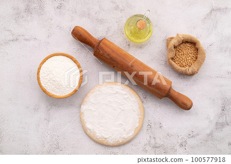 The ingredients for homemade pizza dough with wheat ears ,wheat flour and wheat grains set up on white concrete background. 100577918
