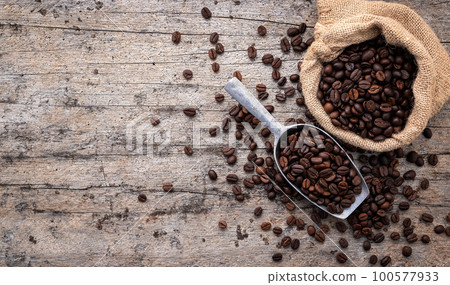 Background of dark roasted coffee beans with scoops setup on wooden background with copy space. Background of dark roasted coffee beans with scoops setup on wooden background with copy space. 100577933