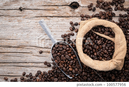 Background of dark roasted coffee beans with scoops setup on wooden background with copy space. Background of dark roasted coffee beans with scoops setup on wooden background with copy space. 100577956