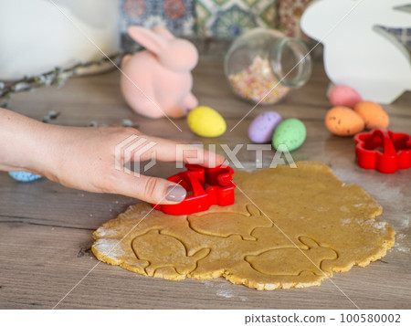 Womens hands close-up kneading ginger dough and carving figurines Womens hands close-up kneading ginger dough and carving figurines 100580002