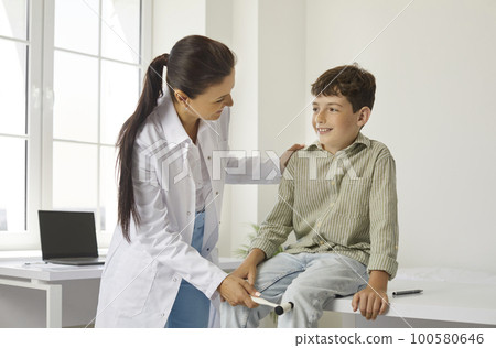 Doctor neuropathologist with special hammer checks knee reflexes on leg preteen boy. Doctor neuropathologist with special hammer checks knee reflexes on leg preteen boy. 100580646