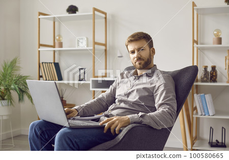 Portrait of a relaxed businessman with a laptop computer sitting in an armchair at home Portrait of a relaxed businessman with a laptop computer sitting in an armchair at home 100580665
