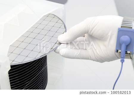 Gloved Hand Holding a Silicon Wafer in plastic holder box used in electronics for the fabrication of integrated circuits. Silicon wafer inspection. 100582013