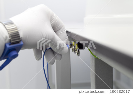 Bracelet on the hand of a man wearing ESD cloth and glove static resistance ESD bracelet or ground equipment, anti-static, used to safely ground is working. Semiconductor manufacturing. Bracelet on the hand of a man wearing ESD cloth and glove static resistance ESD bracelet or ground equipment, anti-static, used to safely ground is working. Semiconductor manufacturing. 100582017