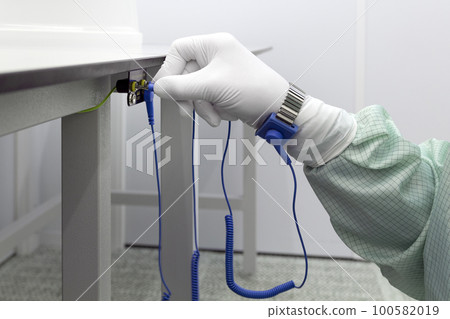 Bracelet on the hand of a man wearing ESD cloth and glove static resistance ESD bracelet or ground equipment, anti-static, used to safely ground is working. Semiconductor manufacturing. 100582019