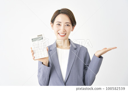 Business woman holding a calculator and pointing to the right with her palm White background 100582539