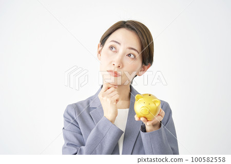 女商人一邊拿著豬存錢罐一邊思考 白色背景 女商人一邊拿著豬存錢罐一邊思考 白色背景 100582558