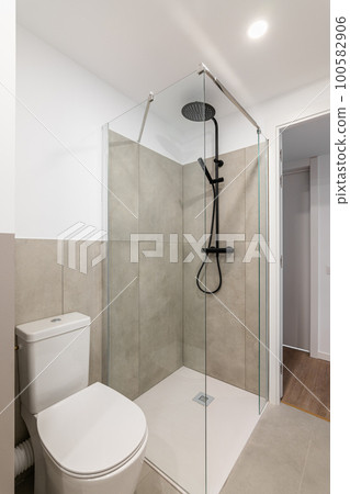 An empty tiny bathroom with a toilet and a glazed shower with gray tiles. The concept of a simple and stylish bathroom in an apartment or luxury hotel An empty tiny bathroom with a toilet and a glazed shower with gray tiles. The concept of a simple and stylish bathroom in an apartment or luxury hotel 100582906