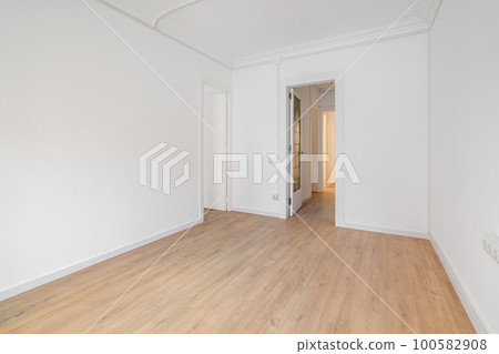 Empty white room with wooden laminate flooring and an open door in new house. Concept of preparing the premises for occupancy and carrying out cosmetic repairs. Copyspace 100582908