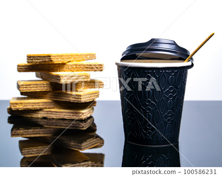 Black paper disposable cups for coffee drinks and waffle cookies on the table. 100586231