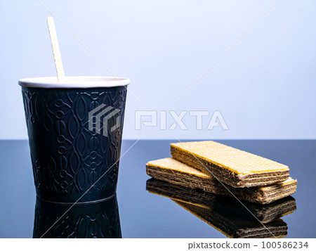 Black paper disposable cups for coffee drinks and waffle cookies on the table. 100586234