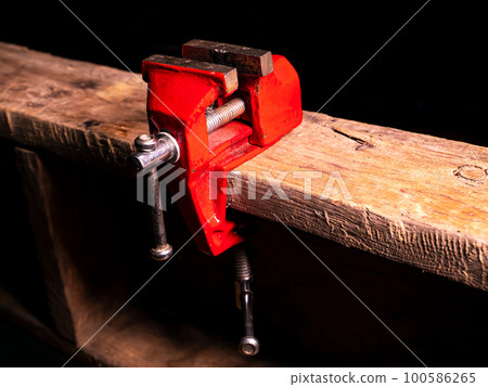 Locksmiths tool metal vise fixed on a wooden table. Locksmiths tool metal vise fixed on a wooden table. 100586265
