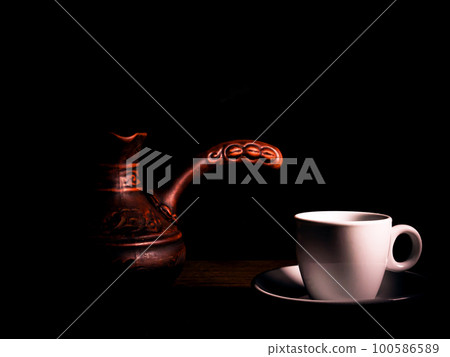 White ceramic coffee cup with saucer and coffee maker on a black background. White ceramic coffee cup with saucer and coffee maker on a black background. 100586589