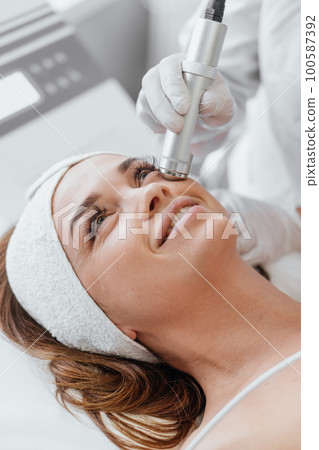 Electroporation without injection mesotherapy. Woman cosmetologist performs cosmetic procedure Electroporation without injection mesotherapy. Woman cosmetologist performs cosmetic procedure 100587392