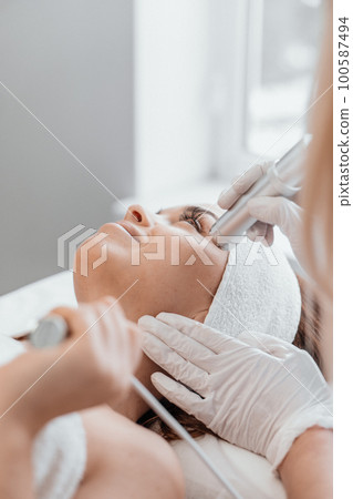 Electroporation without injection mesotherapy. Woman cosmetologist performs cosmetic procedure Electroporation without injection mesotherapy. Woman cosmetologist performs cosmetic procedure 100587494
