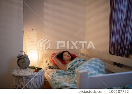 The girl sleeps on a large red pillow on her bed. 100587722