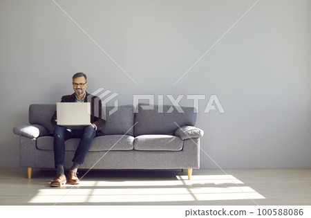 Mature businessman sitting on sofa working with laptop 100588086