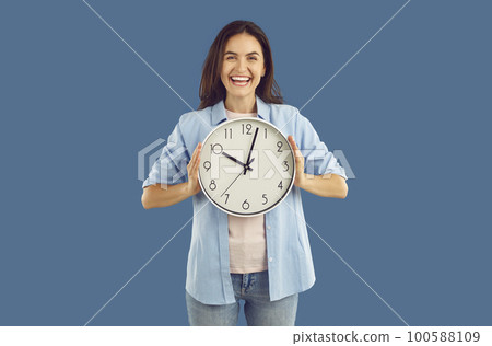Happy excited young woman holding big wall clock Happy excited young woman holding big wall clock 100588109