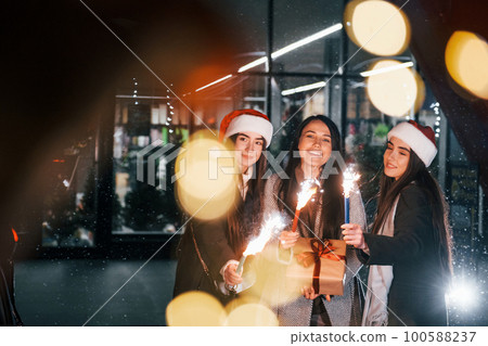 Little fireworks, Bengal lights. Three cheerful women spends Christmas holidays together outdoors. Conception of new year 100588237