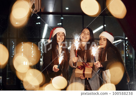 Little fireworks, Bengal lights. Three cheerful women spends Christmas holidays together outdoors. Conception of new year Little fireworks, Bengal lights. Three cheerful women spends Christmas holidays together outdoors. Conception of new year 100588238