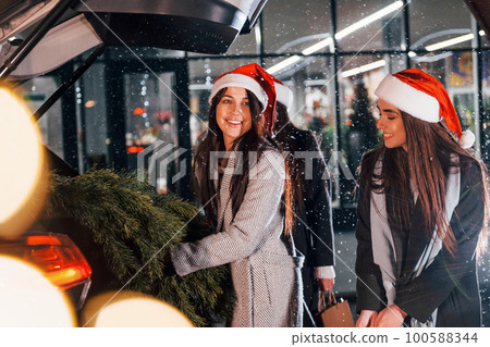 Three cheerful women spends Christmas holidays together outdoors. Conception of new year 100588344