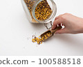 Scooping grains from a jar with a spoon by hand 100588518