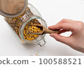 close up of a hand holding a spoon of seeds 100588521