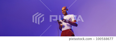 Young sporty man is check fitness app and holding jump rope standing on studio background Young sporty man is check fitness app and holding jump rope standing on studio background 100588677